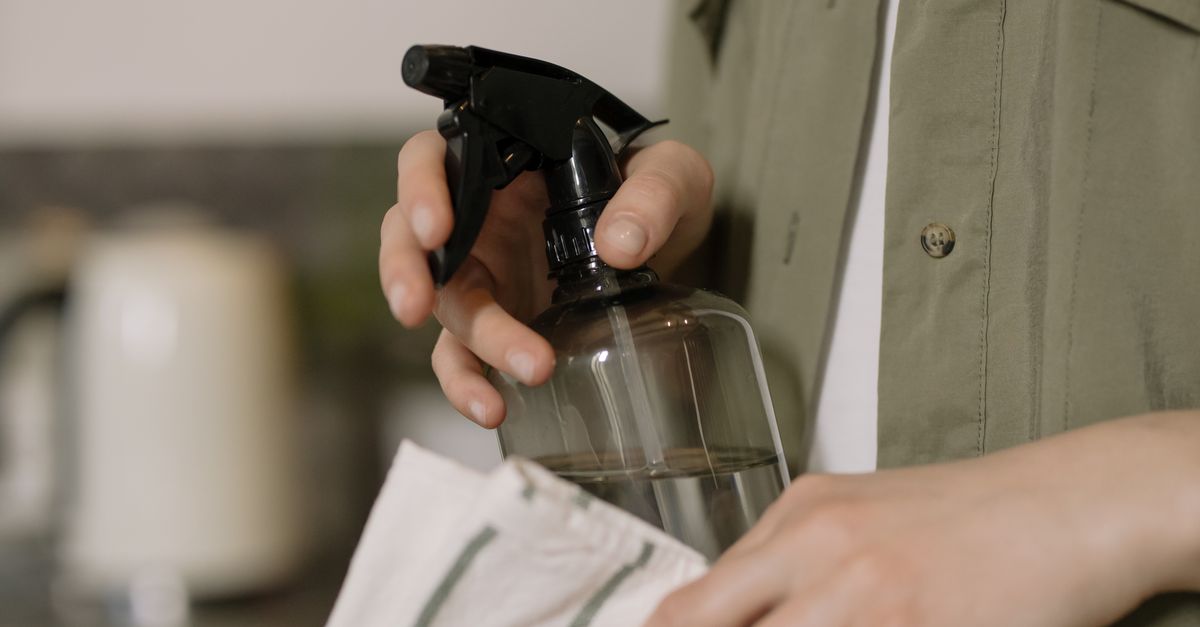 Close-up shot of a person cleaning with a spray bottle and cloth. Ideal for cleaning and home care themes.